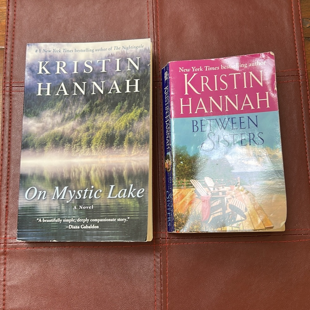 Book duo: Between Sisters and On Mystic Lake—both by Kristen Hannah, paperbacks.